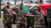 Des membres de l'armée kenyane font le salut militaire à côté du cercueil transportant le corps du chef des forces de défense kenyanes, le général Francis Omondi Ogolla, au complexe sportif d'Ulinzi à Nairobi, le 20 avril 2024. (Photo par LUIS TATO / AFP)