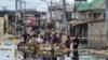 People cross floodwaters in the Pompage district in Kinshasa, Democratic Republic of Congo, on Jan. 9, 2024, following heavy rains. Regional flooding left some 350,000 people in need of humanitarian aid in neighboring Republic of Congo.