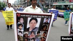 ২০০৪ সালের গ্রেনেড হামলার বার্ষিকী উপলক্ষে নিহতদের ছবির একটি পোস্টার নিয়ে মিছিল করছেন আওয়ামী যুবলীগের একজন সদস্য। (ফাইল ছবি) 
