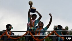 নেপালে সাফ মহিলা চ্যাম্পিয়নশিপ-২০২২ জেতার পর দেশে ফিরে ঢাকায় এক বিজয় শোভাযাত্রায় টুর্নামেন্টের ট্রফিটি উঁচিয়ে ধরে রেখেছে বাংলাদেশ নারী ফুটবল দলের সদস্যরা। ২১শে সেপ্টেম্বর, ২০২২। (ফাইল ছবি)