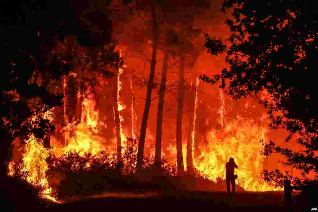 A wildfire burns near Belin-Beliet, France, and officials warned that flare-ups could cause the massive fire to spread in the country&#39;s parched southwest, where fresh blazes have already blackened swathes of land this week.