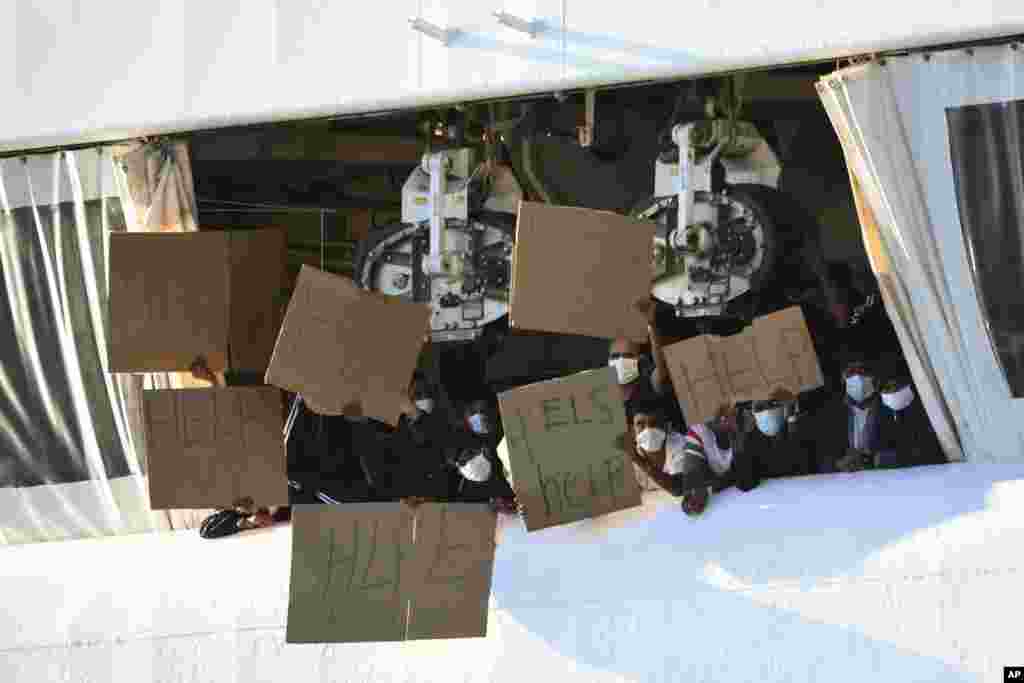 Migrants hold banners asking for help, from a deck of the Norway-flagged Geo Barents ship operated by Doctors Without Borders, in Catania&#39;s port, Sicily, southern Italy. The Geo Barents has been allowed to disembark 357 migrant that Italian authorities defined as &quot;vulnerable people&quot; and minors, while leaving another 215 people that were declared non-vulnerable blocked on board.&nbsp;
