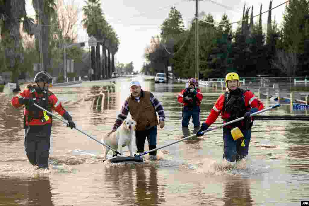 San Diego firefighters help Humberto Maciel rescue his dog from his flooded home in Merced, California, Jan. 10, 2023.&nbsp;Relentless storms were ravaging California again, the latest bout of extreme weather that has left 14 people dead. Fierce storms caused flash flooding, closed key highways, toppled trees and swept away drivers and passengers.&nbsp;