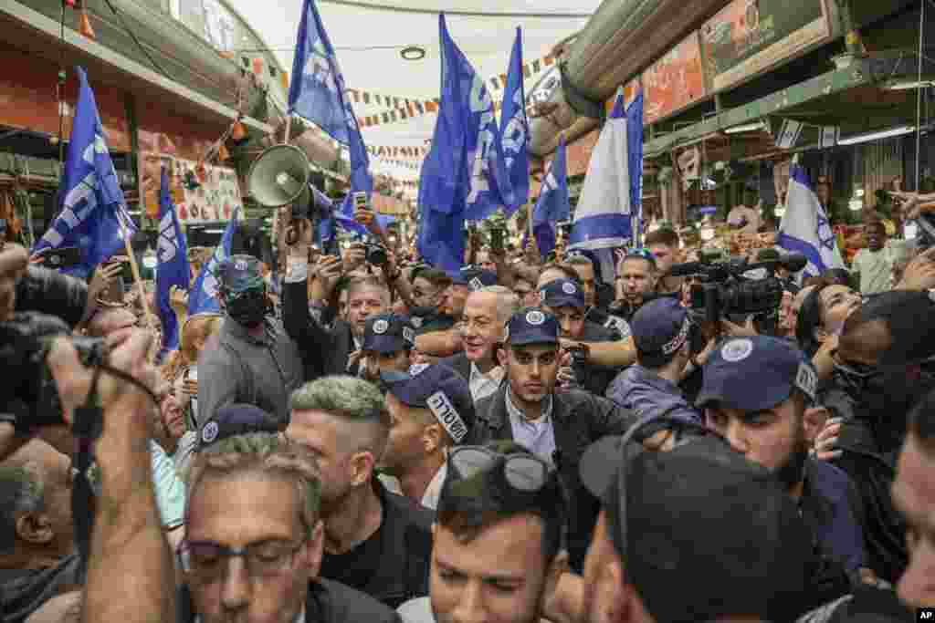 Former Israeli Prime Minister and the head of Likud party Benjamin Netanyahu, center, surrounded by security and his supporters visits at Hatikva Market in Tel Aviv during his campaign ahead of the country&#39;s Nov. 1 election.