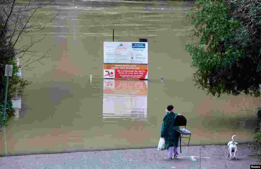 Emily Jean Pierre and her dog Vixen walk near the Russian River where it flooded Johnson&rsquo;s beach in Guerneville, California.