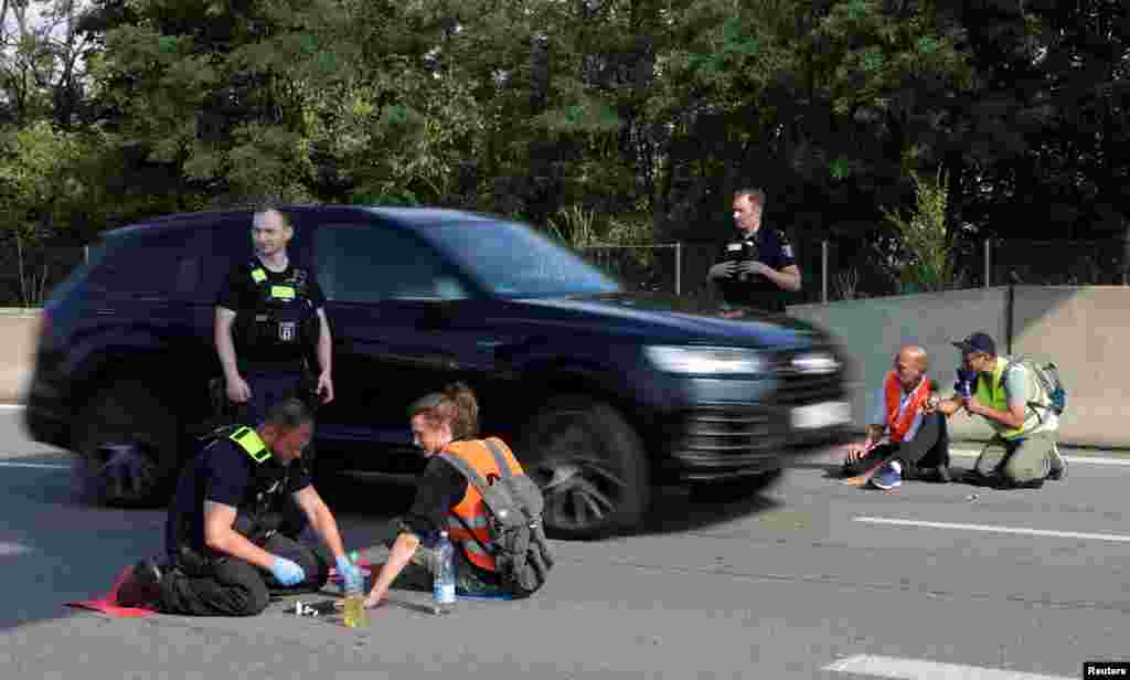 A police officer removes a &quot;Letzte Generation&quot; (Last Generation) activist that glued his hand to the road, as they block a highway for an end to fossil fuels and against oil drilling in the North Sea, in Berlin, Germany.
