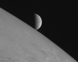 FILE - The icy moon Europa rises above Jupiter's cloud tops in this undated image taken by NASA spacecraft New Horizons.