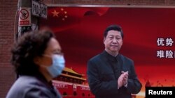 资料照：一名戴口罩妇女从习近平画像前走过。