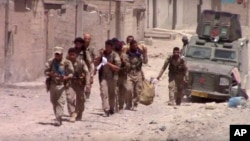 Esta imagen tomada de un video divulgado el martes, 4 de julio de 2017, suministardo por Furat FM, un grupo activista sirio kurdo, muestra a combatientes de las Fuerzas Democráticas Sirias, respaldadas por EE.UU. en el este de Raqqa, Siria.
