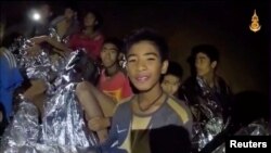 Un niño del equipo de fútbol juvenil menores de 16 años atrapados en una cueva en Tham Luang, Tailandia, envuelto en una frazada, reacciona a la cámara. Imagen tomada de un video el 3 de julio de 2018.