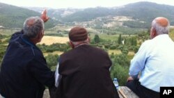 Rûniştvanên gundê Guveççî li hêla Sûrîyê ya tixubê meze dikin. Hezîran, 11 2011