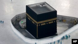 FILE - Workers disinfect the grounds around the Kaaba, a cubic building at the Grand Mosque in the Muslim holy city of Mecca, Saudi Arabia, March 7, 2020.