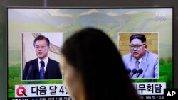 一名女子走过韩国首尔火车站正在播放韩国总统文在寅（左）和朝鲜领导人金正恩画面的电视屏幕。（2018年3月29日）
