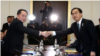 El jefe de la delegación norcoreana, Ri Son Gwon, se da la mano con su par surcoreano, Cho Myoung-gyon, mientras intercambian documentos tras su encuentro en la villa fronteriza de Panmunjeom, en la zona desmilitarizada que divide a ambos países, 9 de ene