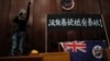 一名进入香港立法会的抗议者站在挂在立法会内的香港殖民地旗帜旁使用扩音喇叭讲话。（2019年7月1日）
